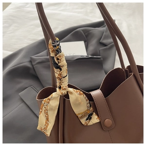 Close-up of a large dark brown tote bag featuring a decorative printed silk scarf on handle