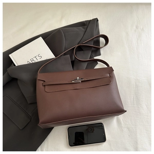 Flat lay of a dark brown leather crossbody bag with silver twist lock and fashion accessories