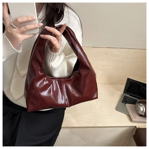 Detail of burgundy glossy faux leather hobo tote bag with stylish natural folds
