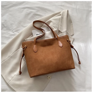 Dettaglio borsa tote in pelle scamosciata marrone con coulisse laterali e texture spessa