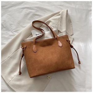 Dettaglio di una borsa tote in pelle scamosciata marrone con anelli metallici decorativi