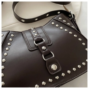 Gros plan sur un sac besace marron vintage avec rivets argentés et boucles métalliques