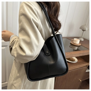 Chic matte black leather tote bag worn with a beige trench coat for a stylish office look