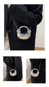 Detail of silver acrylic evening bag with wave texture and metal ring handle
