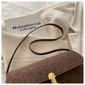 Close-up of brown suede shoulder bag featuring a vintage gold U-shaped metal buckle