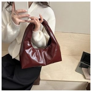 Macro view of burgundy patent leather bag showing glossy texture and vertical stitching