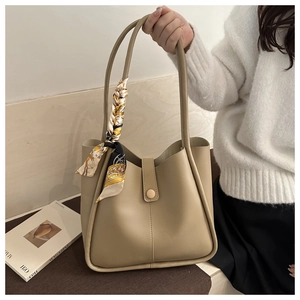 Detail of khaki tote bag with elegant floral scarf and buckle closure held by model