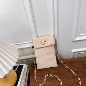 Piccola borsa a tracolla beige trapuntata con catena dorata su un tavolo in legno
