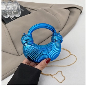 Macro detail of electric blue crescent bag with textured pleats and golden chain strap