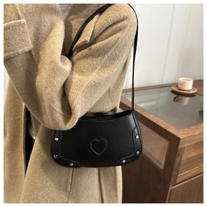 Detail of black faux leather underarm bag with crocodile pattern and silver stud heart