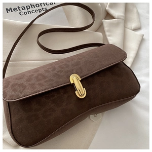 Close-up of brown suede shoulder bag featuring a prominent gold horseshoe buckle
