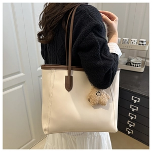 Detail view of large cream tote bag with brown straps and cute bear charm pendant