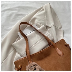 Dettaglio della borsa tote in pelle scamosciata marrone con ciondolo a cucciolo