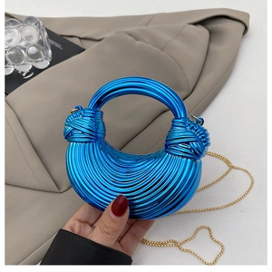 Detail of blue metallic acrylic handbag featuring a knotted handle and gold chain strap