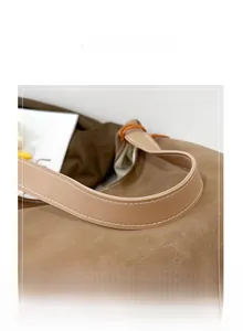 Close-up of brown leather bag handle featuring white contrast stitching and texture