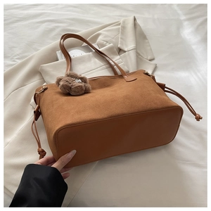 Borsa tote in camoscio caramello con ciondolo a orsetto su abbigliamento elegante