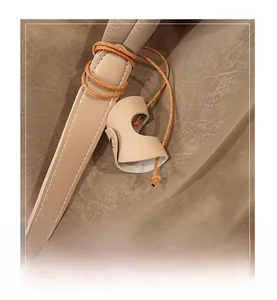 Detail of soft leather shoulder strap with orange lanyard and white stitching on beige bag
