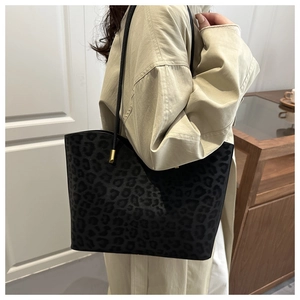 Detail of black leopard print tote bag with textured finish and golden metal buckle
