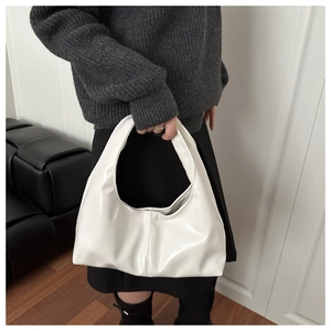Detailed view of a white glossy hobo bag with elegant pleats and minimalist leather texture