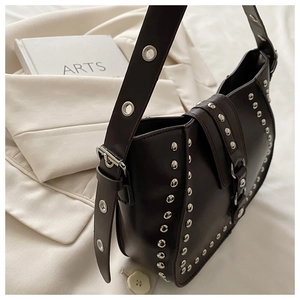 Détail du sac besace en cuir marron avec clous argentés et bandoulière réglable