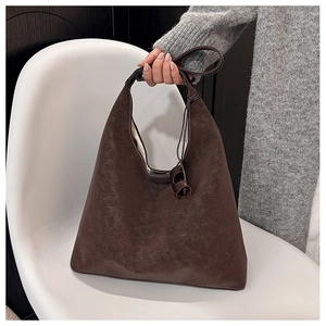 Close-up of vintage dark brown faux leather tote bag with distressed texture on a chair