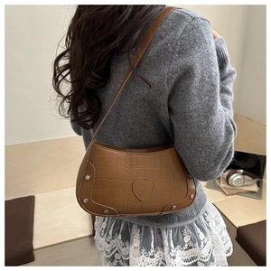 Detail of vintage brown crocodile pattern underarm bag with silver rivets and heart decoration