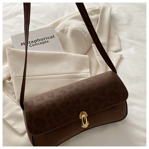 Detail of vintage leopard print flap and gold twist lock on brown suede shoulder bag