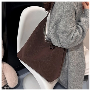 Detail of dark brown tote bag with white contrast stitching on model in a grey sweater