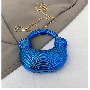 Detail of blue metallic acrylic handbag featuring textured stripes and a knot handle design