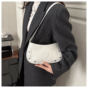 Close-up of white crocodile pattern underarm bag with heart patch and black studs