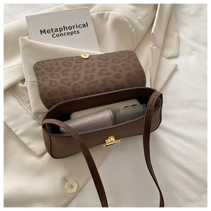 Deep brown baguette bag with leopard print lining and gold clasp on light jacket