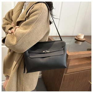 Detailed view of black vintage leather handbag with silver lock and buckle on beige coat