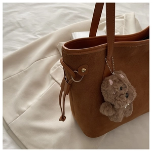 Dettaglio della borsa tote in pelle scamosciata marrone con coulisse e ciondolo di peluche