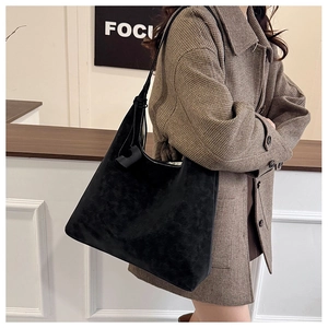 Detail of minimalist black matte tote bag worn with a brown plaid coat for commuting