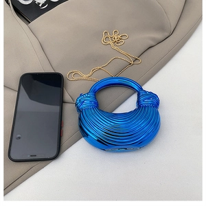 Macro detail of electric blue acrylic bag with spiral texture and gold chain strap