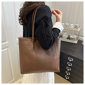 Brown leather tote bag featuring sleek side profile and slim shoulder strap detail