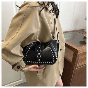 Detail of black leather crescent bag with silver rivets and vintage punk aesthetic