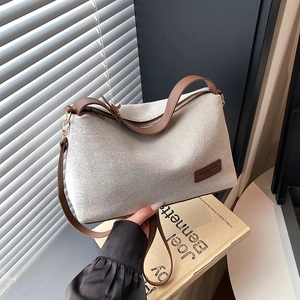Minimalist beige woven canvas shoulder bag with brown leather straps and vintage gold hardware