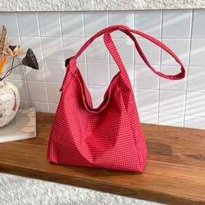 Sac fourre-tout à carreaux rouges avec bandoulière réglable sur une table en bois