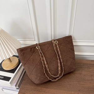 Deep brown quilted tote bag with golden chain strap on a wooden table setup