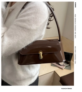 Gros plan d'un sac baguette en cuir verni marron avec une boucle en métal doré