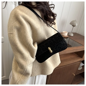 Detail of black leopard print underarm bag with gold metal buckle on a shoulder strap