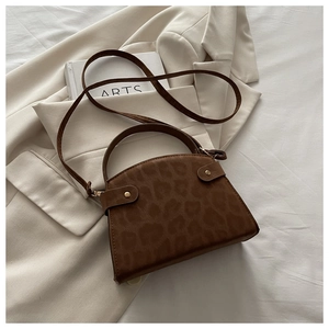 Detailed view of leopard print texture on a vintage trapezoid handbag with gold studs