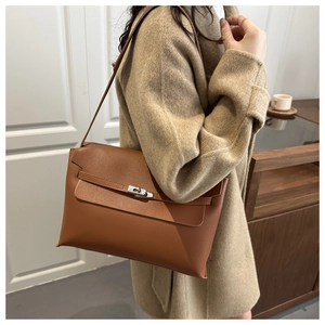 Macro detail of brown leather tote showing the silver metal turn-lock and flap closure