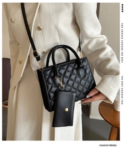 Detail of black quilted shoulder bag with matching mini coin purse and gold hardware