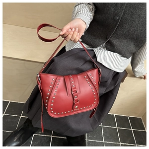 Détail du sac besace en cuir rouge avec clous argentés et boucle au design vintage punk