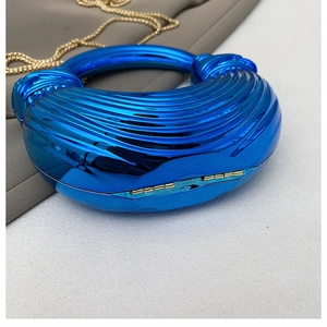 Detail of royal blue metallic evening clutch bag with round handle and gold chain