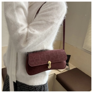 Detailed view of burgundy leopard print suede bag with a gold oval rotating buckle lock