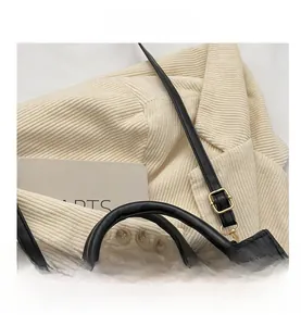 Close-up of black quilted small square bag showing round handle and adjustable strap