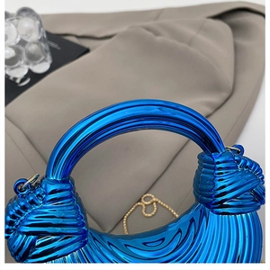Macro shot of electric blue metallic clutch bag with vertical pleated texture and knotted handle